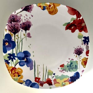 May include: A square white plate with a colorful floral design. The flowers are painted in watercolor style with shades of red, purple, blue, yellow, and green. The plate has rounded corners and a smooth surface.