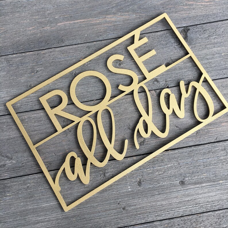 May include: Gold-colored wooden sign with the text "Rose all day" in a decorative font.