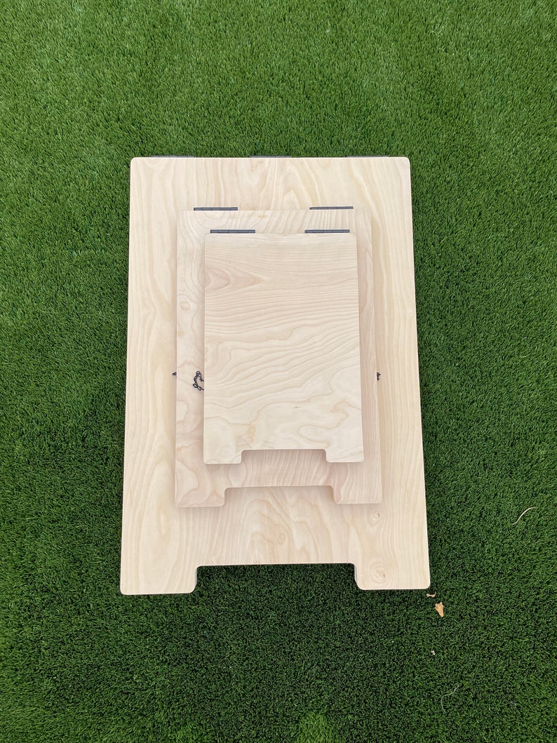 May include: Three wooden cutting boards stacked on top of each other. The boards are all made of light wood and have a natural finish. The boards are all rectangular in shape and have rounded corners.