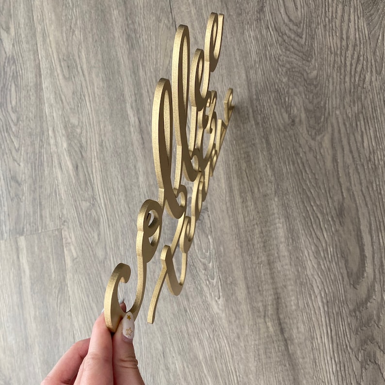 May include: Gold-colored wooden sign with the words "Hello Gorgeous" in a cursive font.
