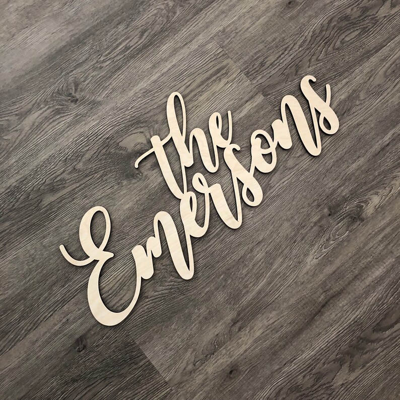 May include: A wooden sign with the name 'The Emersons' in cursive lettering, painted in a light brown colour.