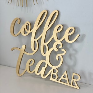 May include: Gold wooden sign with the words "coffee & tea bar" in a cursive font.