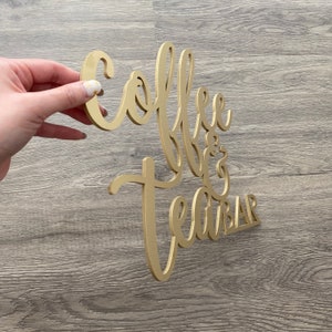 May include: Gold-colored wooden sign with the words "Coffee & Tea Bar" in a cursive font.