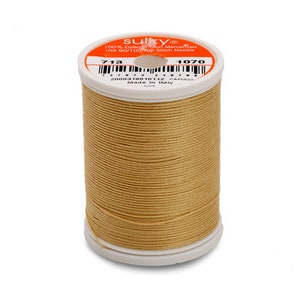 May include: A spool of Sulky brand thread in a light tan color. The spool has a white base and top with an orange label. The label includes the text "100% Cotton Mercerized" and the numbers "713" and "1070".