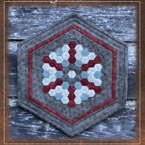 Pode incluir: Um corredor de mesa acolchoado hexagonal com um design de floco de neve em tons de cinza, vermelho e branco. O corredor de mesa é chamado de "Charlotte's Web".