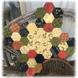 May include: A hexagonal patchwork quilt with a Christmas theme. The quilt is made of various fabrics in shades of red, green, black, and white. The fabrics feature patterns of plaid, musical notes, holly, and stripes.