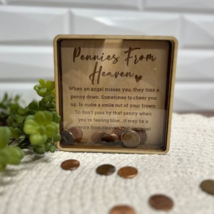 May include: A wooden box with a glass front that says "Pennies From Heaven" and has a quote about finding pennies. The box is filled with copper pennies.