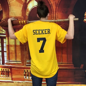 May include: A yellow t-shirt with the word "SEEKER" and the number "7" printed on the back.