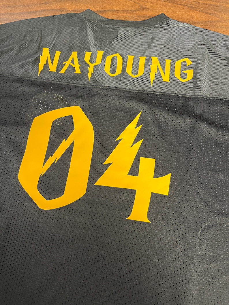 Pu&ograve; includere: Maglia da calcio in mesh nera con il nome "NAYYOUNG" e il numero "04" in giallo con disegni di fulmini.
