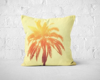 May include: A yellow throw pillow featuring a silhouette of a palm tree in shades of orange and red.