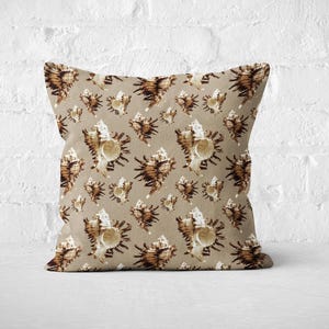 Może przedstawiać: Beżowa poduszka z powtarzającym się wzorem brązowych muszli. Poduszka wykonana jest z miękkiej, fakturowanej tkaniny.
