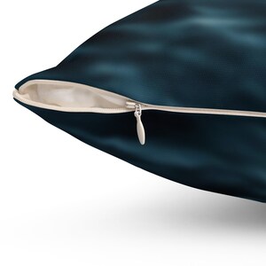 May include: A dark teal cushion with a zip closure. The cushion features a textured, abstract design in shades of teal and navy blue. The zip is white.