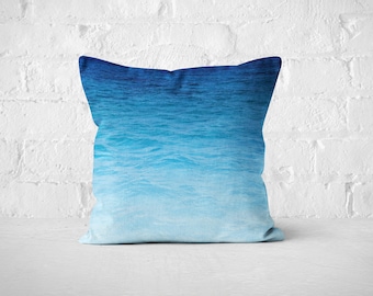May include: A blue and white throw pillow featuring a watercolour-style image of ocean waves.