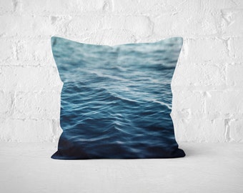 May include: A blue and white cushion with a photograph of ocean waves.