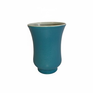 May include: A teal-colored ceramic vase with a flared top and a rounded base. The interior rim is a light cream color. The vase has a smooth, matte finish and a symmetrical, curved shape. It stands on a white background.