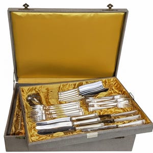 May include: A silver flatware set in a gray case with a yellow satin lining. The set includes forks, knives, spoons, and serving pieces. The case is open, revealing the neatly arranged silverware.
