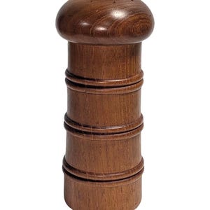 May include: A white ceramic mug with a black handle and the text "But First, Coffee" in a bold, black font. The mug is set against a blurred background, highlighting its simple design.