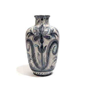 May include: A decorative ceramic vase with a crackle finish. The vase features a blue and white floral design with stylized leaves and swirls. The vase has a rounded body and a narrow neck.