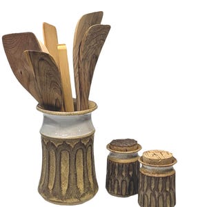 May include: A set of three ceramic mugs with a speckled, matte finish. Each mug features a different color: light blue, cream, and gray. The mugs have a simple, modern design and a comfortable handle.