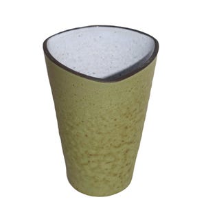 May include: A handmade, light green ceramic tumbler with a textured surface. The interior is white, and the rim is outlined with a dark brown band. The tumbler has a unique, slightly triangular shape.