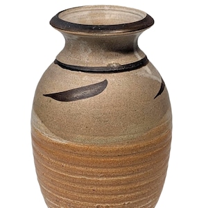 May include: A handcrafted ceramic vase with a rounded body and a narrow neck. The vase features a textured, earthy color palette with brown and tan tones. Dark brown curved accents and a black band add detail. A decorative piece for home decor.