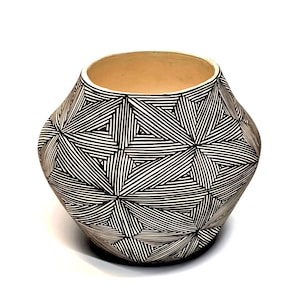 May include: A handcrafted ceramic vase with a geometric black and white pattern. The vase has a wide, rounded body and a beige interior. The exterior features a repeating design of black lines forming triangular shapes.