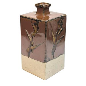 May include: A square ceramic vase with a brown and beige color scheme. The top and sides are brown with a textured, crackled appearance and abstract gold-colored accents. The bottom half is beige.