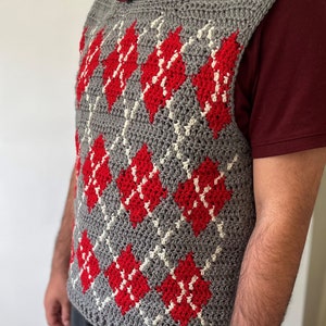 May include: A gray crocheted vest with a diamond pattern in red and white.