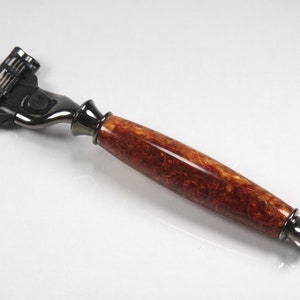 May include: A safety razor with a black and silver head and a brown wooden handle with a marbled pattern.