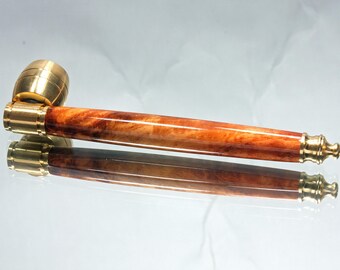 May include: A handcrafted tobacco pipe with a wooden body and brass accents. The pipe features a rich, reddish-brown wood grain and polished brass fittings. The pipe is approximately 15 cm long.