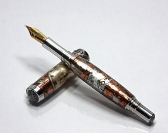 May include: A silver and copper fountain pen with a gold-plated nib. The pen has a textured, metallic finish and a unique design.