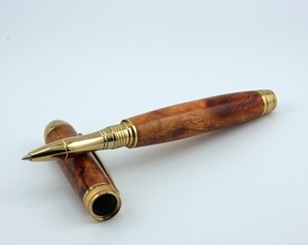 May include: A wooden rollerball pen with its cap beside it. The pen features a brown, wood-grain barrel and gold-coloured metal accents. The cap is also brown with gold accents. The pen is designed for writing.