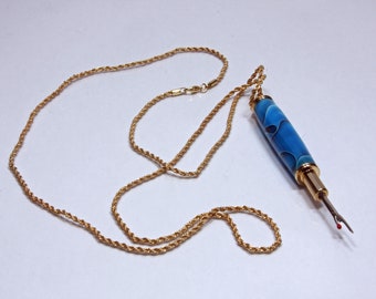 May include: A gold chain necklace with a blue and gold threader attached. The threader has a sharp point at the end.