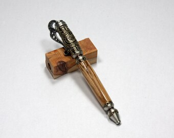 May include: A wooden pen with a silver and gold metal design. The pen is on a small wooden block.