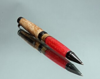 May include: A red and wood pen with a black metal tip and a silver clip. The pen has a red glitter finish and a wood grain pattern.