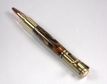 May include: A gold and copper bullet pen with a brown and black marbled design. The pen has a twist mechanism and a clip.
