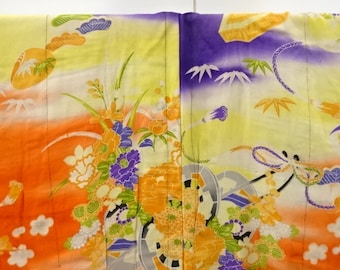 Pode incluir: Um quimono japonês tradicional com um vibrante padrão floral laranja, amarelo e roxo. O tecido apresenta um design degradê com detalhes intrincados e uma textura tecida.