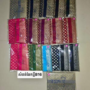 May include: A collection of fabric pieces in various colors, including pink, green, blue, and black, each with a gold patterned design. The fabrics are packaged in clear plastic and arranged in rows. The text "សាច់គោកខ្នាB16" is visible.