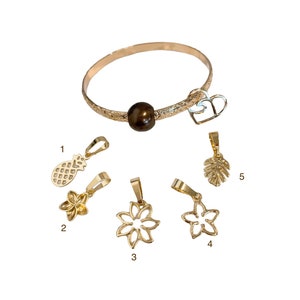 May include: A gold bracelet with a brown pearl charm and five different charms: a pineapple, two flowers, a leaf, and a heart. The charms are numbered 1 through 5.