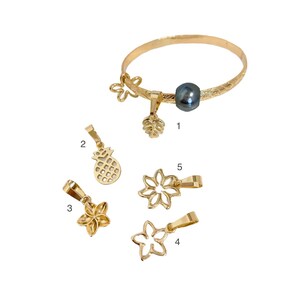 May include: A gold bracelet with a black pearl charm and five additional charms: a pineapple, a flower, a leaf, and two more flowers. The charms are numbered 1 through 5.