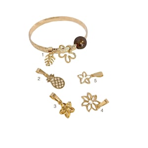 May include: Gold bracelet with a variety of charms, including a pineapple, a flower, and a leaf. The bracelet also has a brown pearl charm.