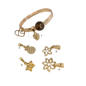 May include: Gold bracelet with a brown pearl charm and five additional charms: a heart, a pineapple, two flowers, and a star. The charms are numbered 1 through 5.