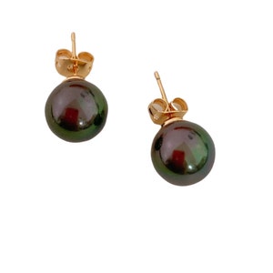 May include: A pair of gold stud earrings with black pearl accents. The pearls have a green iridescent sheen.