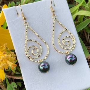 May include: Gold teardrop earrings with a textured swirl design and a black pearl dangle.