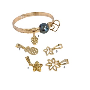 May include: Gold bracelet with a black pearl charm and five additional charms: a pineapple, two plumeria flowers, and two leaves. The charms are numbered 1 through 5.