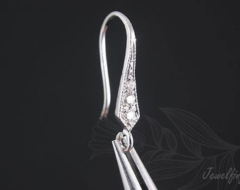 May include: Silver earring with a teardrop-shaped design and three small clear stones.