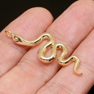 Peut inclure: Un pendentif en forme de serpent doré avec une boucle pour l'attacher à un collier ou un bracelet.
