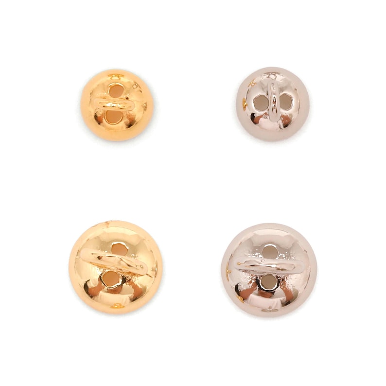May include: Four round buttons in gold and silver. The buttons are slightly domed with two sewing holes. The gold buttons are shiny, while the silver ones have a more muted, metallic look. Ideal for sewing projects.