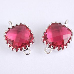 Puede incluir: Dos abalorios en forma de corazón plateados con un centro de cristal rojo. Los abalorios tienen un borde decorativo y un bucle para sujetarlos a un collar o pulsera.