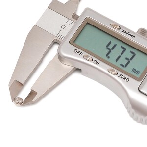 May include: A digital caliper measuring a small, round object. The digital display shows a measurement of 4.73 mm. The caliper is silver and has mm/inch and zero settings.